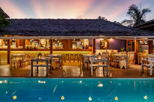 a restaurant with tables and chairs next to a swimming pool at Pousada El Gordo in Trancoso