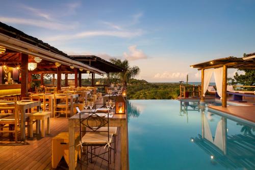 a restaurant with a pool with tables and chairs at Pousada El Gordo in Trancoso