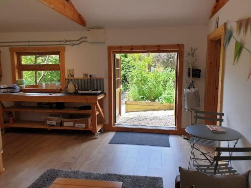 a living room with a desk and a sliding glass door at The Potting Shed near Tenby, 100" Projector, Four poster bed, On-site HOT TUB access via Spa Pack in Tenby