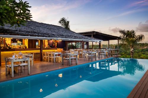 a restaurant with a pool and tables and chairs at Pousada El Gordo in Trancoso