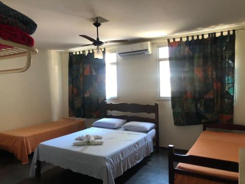a bedroom with a bed with a white blanket and two windows at Pousada de Ubu in Anchieta