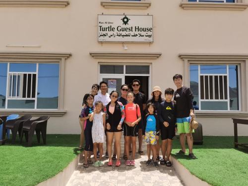 a group of people posing for a picture in front of a building at Turtle Guest House in Sur