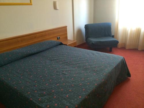 a bedroom with a bed and a blue chair at Hotel Arcobaleno in Vimodrone