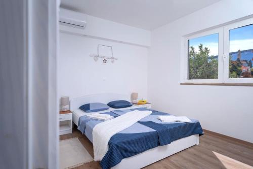 a white bedroom with a bed and a window at AWAKEN Gorgeous Sea View Apartment in Hvar
