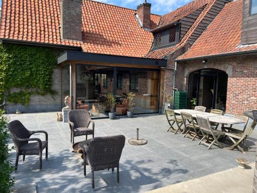 a patio with chairs and a table in front of a building at Hoeve Hooierzele in Waasmunster