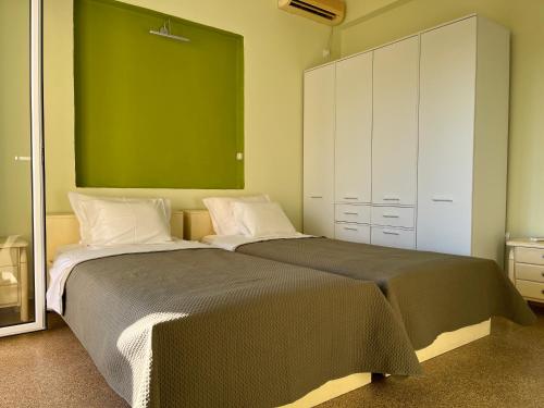 1 dormitorio con 2 camas y pared verde en Athens Riviera: 2 bed / 3' walk from the beach, en Aghia Marina