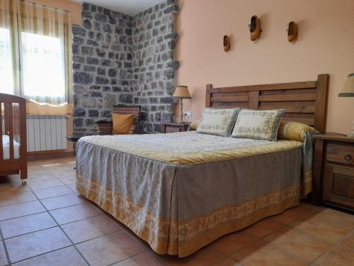 a bedroom with a large bed and a stone wall at Casa Rural El Pinar in Acebedo
