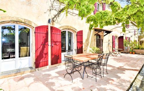 une table et des chaises devant un bâtiment avec portes rouges dans l'établissement Lovely Home In Pont-Saint-Esprit, à Pont-Saint-Esprit
