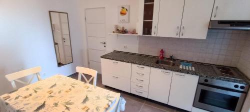 een keuken met witte kasten, een tafel en een wastafel bij Apartment Tena in Novalja