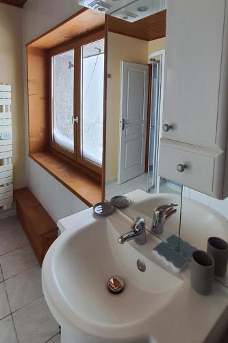 une salle de bain avec un lavabo blanc et un miroir dans l'établissement Le Chalet de Poche - Gite 2 étoiles - 5 pers, à Habère-Poche