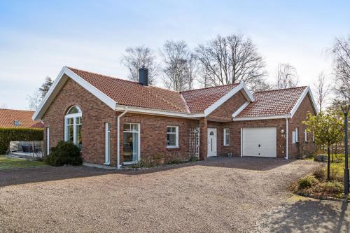 a brick house with a garage on a driveway at Luxury three-bedroom modern family home in Båstad in Båstad