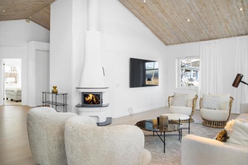 a living room with white furniture and a fireplace at Luxury three-bedroom modern family home in Båstad in Båstad
