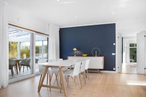a dining room with a white table and chairs at Luxury three-bedroom modern family home in Båstad in Båstad