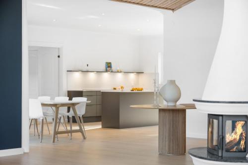 a kitchen and dining room with a table and a fireplace at Luxury three-bedroom modern family home in Båstad in Båstad