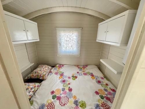 a bed in a small room with a window at Pipowagen aan zee in Bergen aan Zee