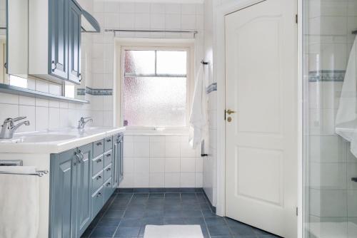 a white bathroom with a sink and a tub at Luxury three-bedroom modern family home in Båstad in Båstad
