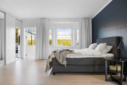 a bedroom with a bed in a room with windows at Luxury three-bedroom modern family home in Båstad in Båstad