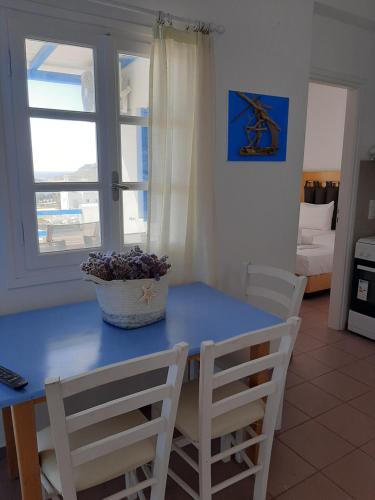 a blue table and chairs in a room with a window at Chaniotis Studios in Kalafatis