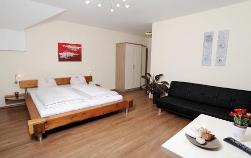 a living room with a bed and a black couch at Gasthof-Pension Boxleitenmühle in Waldkirchen