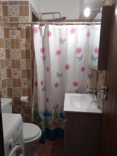 a bathroom with a shower curtain with a toilet and a sink at Eliza Apartments in Rethymno Town