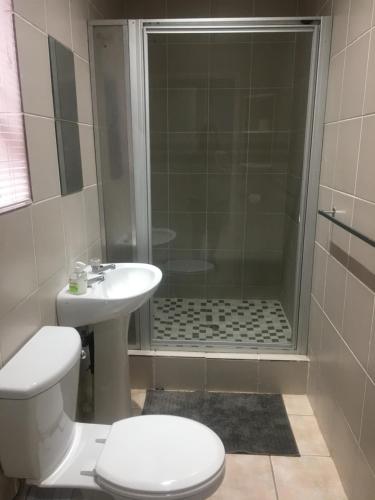 a bathroom with a shower and a toilet and a sink at Rest Assured in Roodepoort