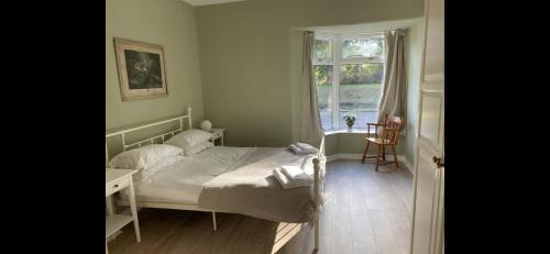 Schlafzimmer mit einem Bett, einem Fenster und einem Tisch in der Unterkunft Peaceful woodland cottage with fireplace in Elie