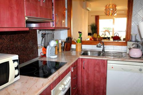a kitchen with red cabinets and a sink at Gran Calahonda Beach near Marbella in Málaga