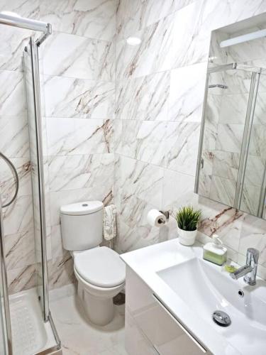 a white bathroom with a toilet and a sink at Gran Calahonda Beach near Marbella in Málaga