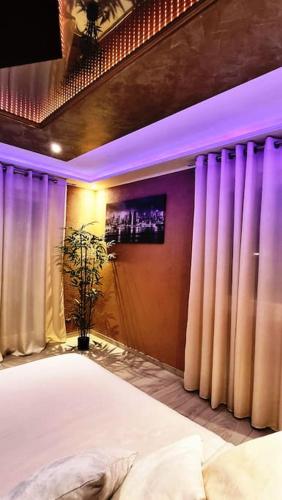 a bedroom with a large bed with purple lighting at RoyalSpa appartement d'amour avec jacuzzi privatif in Strasbourg