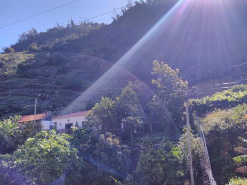 a beam of sunlight shining on a hill with trees at casa da fajã in Funchal