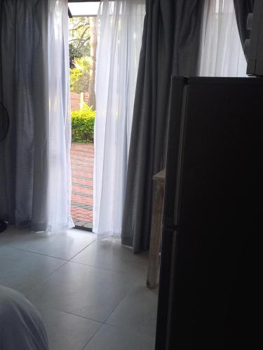 1 dormitorio con una ventana con cortinas blancas en Lime Court Three en Pretoria