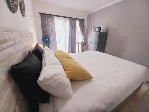 a bedroom with a white bed with yellow pillows at Lime Court Three in Pretoria