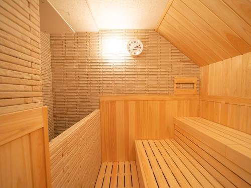 eine Holzsauna mit einer Uhr an der Wand in der Unterkunft Shinsaibashi ARTY Inn in Osaka