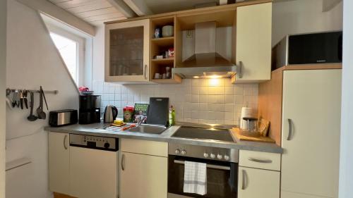 a kitchen with white cabinets and a sink at Gemütliche Maisonettewohnung mit Dachterrasse am Schloß in Oldenburg