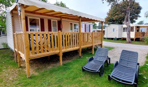 two chairs sitting on a deck in front of a house at Mobil Home Camping Les VIVIERS, Claouey in Claouey