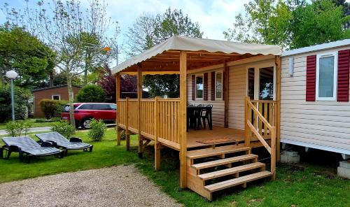 a wooden cabin with a porch and a deck at Mobil Home Camping Les VIVIERS, Claouey in Claouey