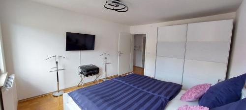 1 dormitorio con 1 cama y TV en la pared en FeelHome Ferienwohnung Tuttlingen en Tuttlingen