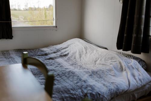 an unmade bed in a bedroom with a window at De la Rue Pipowagens in Sleeuwijk