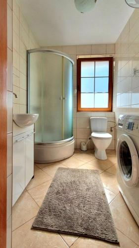 a bathroom with a shower and a washing machine at Dom letniskowy Narie in Morąg