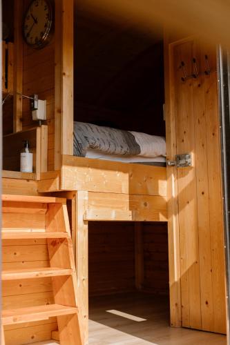 a wooden bunk bed in a room with a clock at De la Rue Pipowagens in Sleeuwijk