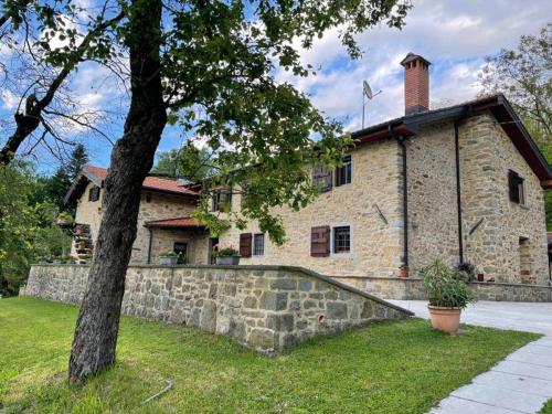 a large stone building with a tree in front of it at Il paradiso delle beccacce in Popiglio