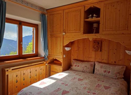 Lagolo di CalavinoにあるChalet nel bosco con lago e panorama mozzafiatoのベッドルーム1室(ベッド1台、大きな窓付)