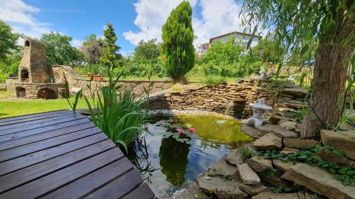 a pond in a garden with a wooden deck at Clara Valis - Village House in Doľany