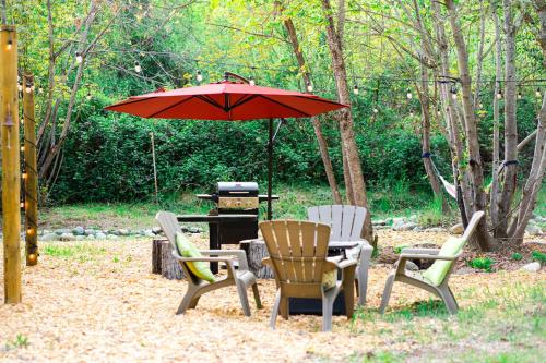 a table and chairs with an umbrella and a grill at Cozy Wild West Covered Wagon next to River in Grants Pass