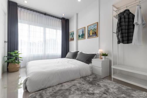 a white bedroom with a large bed and a window at Ozzy's home@Banchang in Ban Chang