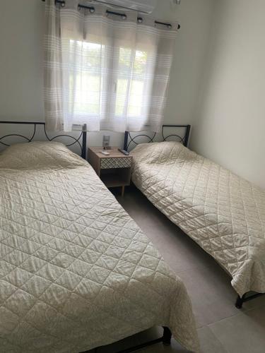 two twin beds in a bedroom with a window at M & F HOUSE (παραλία Μαρκοπούλου Ωρωπού) in Oropós