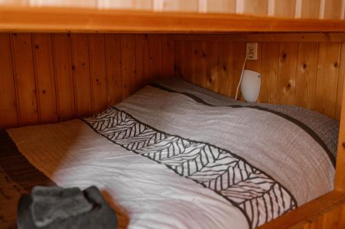 a bed in a room with a wooden wall at De la Rue Pipowagens in Sleeuwijk