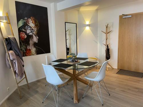 a dining room with a glass table and white chairs at Saga Apartments Akureyri in Akureyri