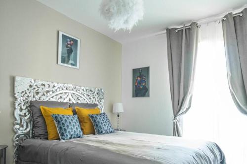 una camera da letto con un letto con cuscini gialli e blu di Bien chez soi à Evry appt 53m2 balcon parking a Évry-les-Châteaux