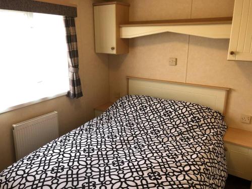 a bedroom with a bed with a black and white comforter at Hylton Park Silloth Caravan Holiday Homes in Silloth
